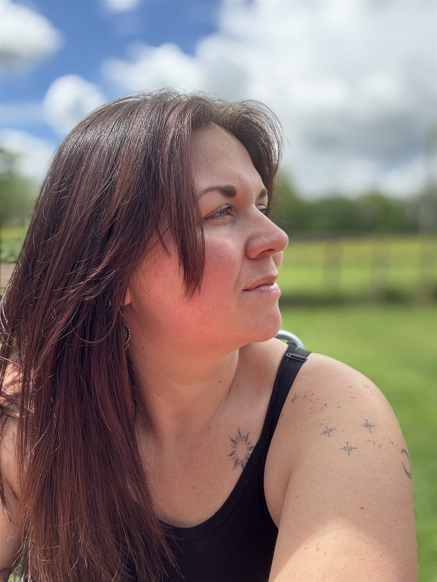 Hannah Monksummers in profile, smiling in a grassy field