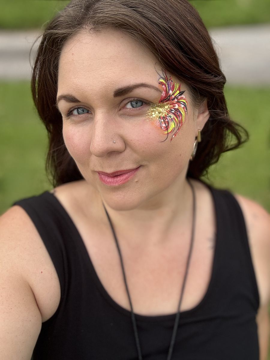 Hannah Monksummers with fiery phoenix-feather face paint over one eye
