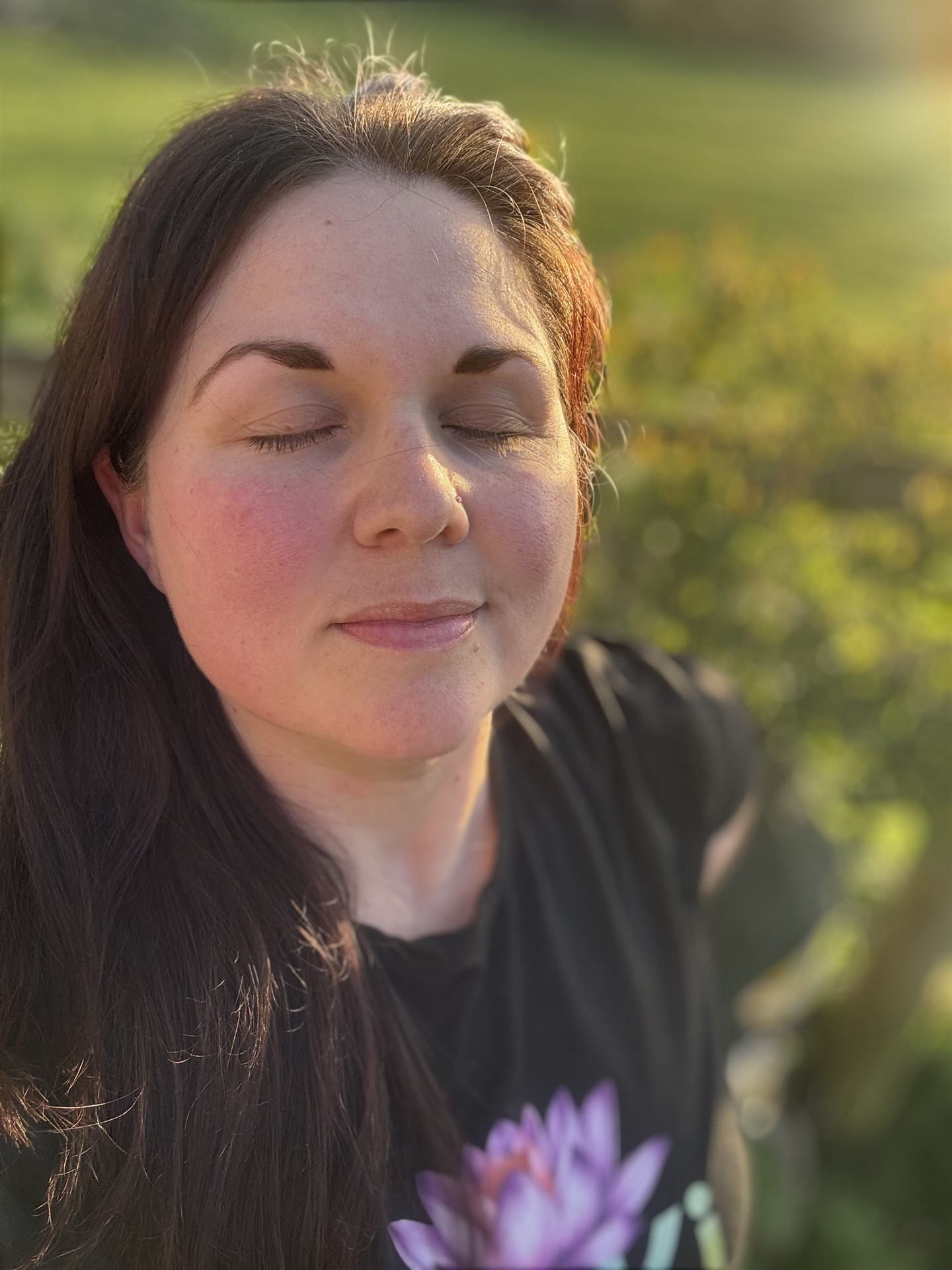 Hannah Monksummers, eyes closed in golden-hour light, holding a lotus flower